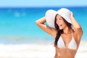 A girl in bikini and wearing sun hat at beach