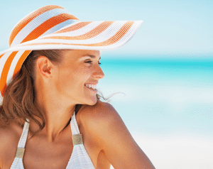 Retrato de mujer joven feliz en traje de baño y sombrero de playa mirando en su dirección izquierda