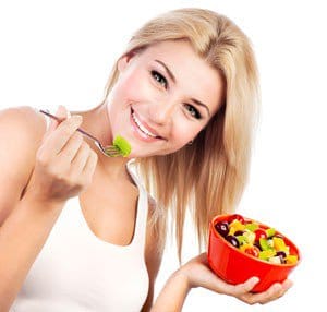 Chica sonriendo y comiendo una dieta saludable