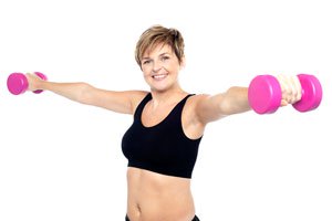 Fit woman working out with pink dumbbells